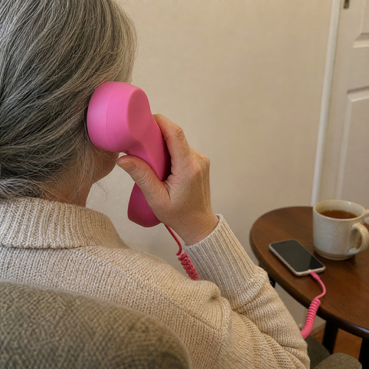 A woman enjoying a call on a pink wired handset